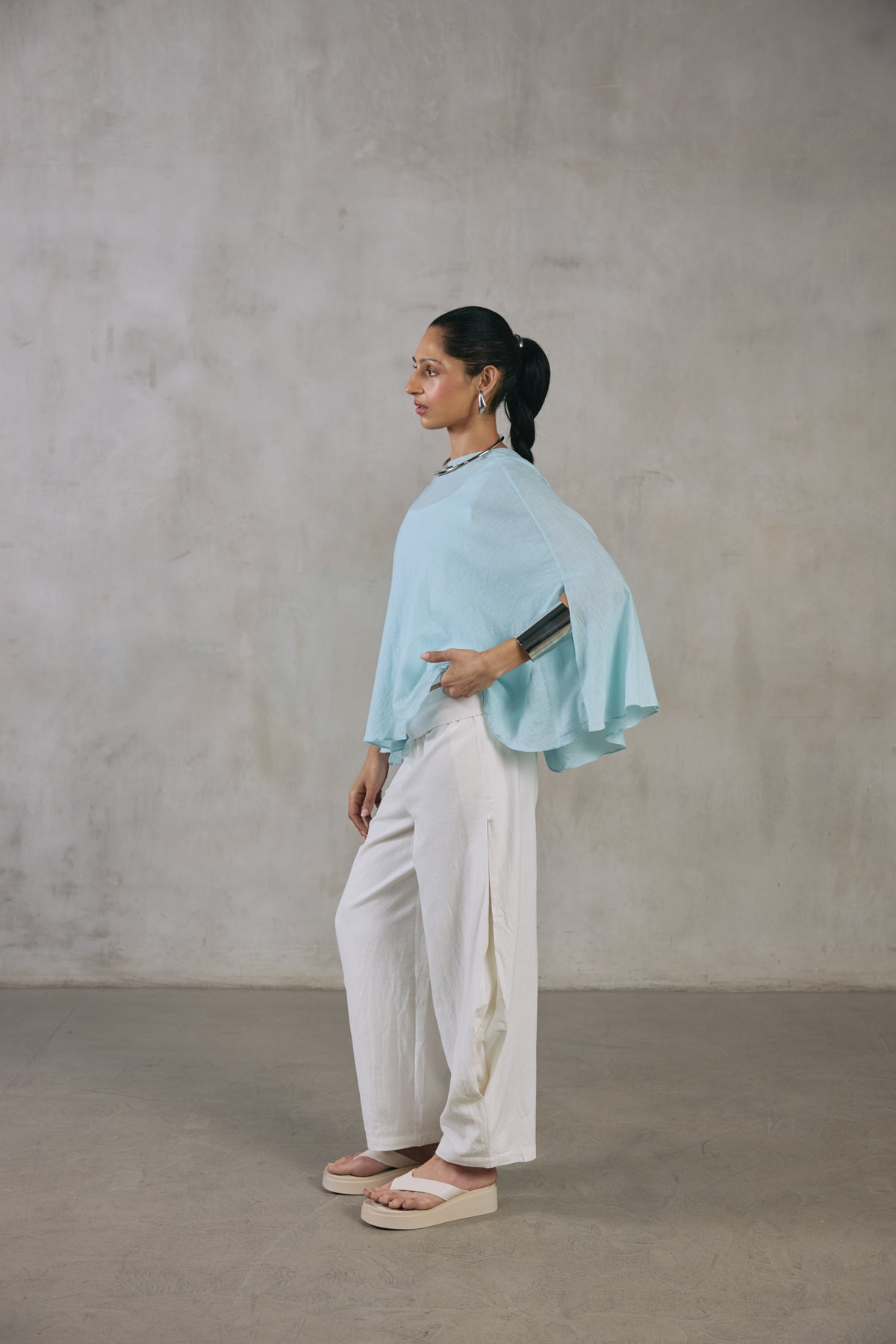 Light blue cape poncho with one arm extended, showing the weightless drape