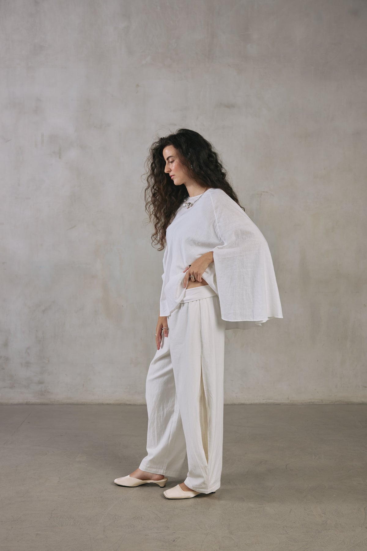Ecru cape poncho with one arm extended, showing the full width of the weave