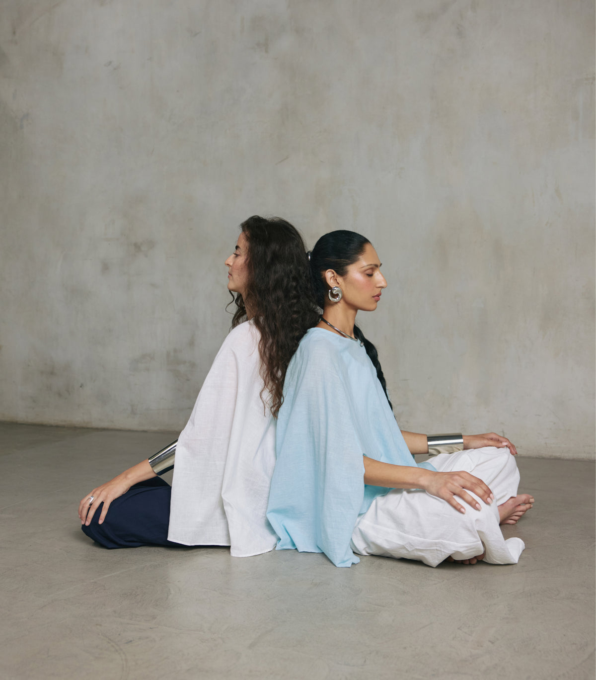 Two women seated in the Cape Poncho in Ecru and Light Blue